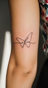 Minimalistic single-line butterfly tattoo on inner arm, soft natural light, subtle skin texture, close-up.